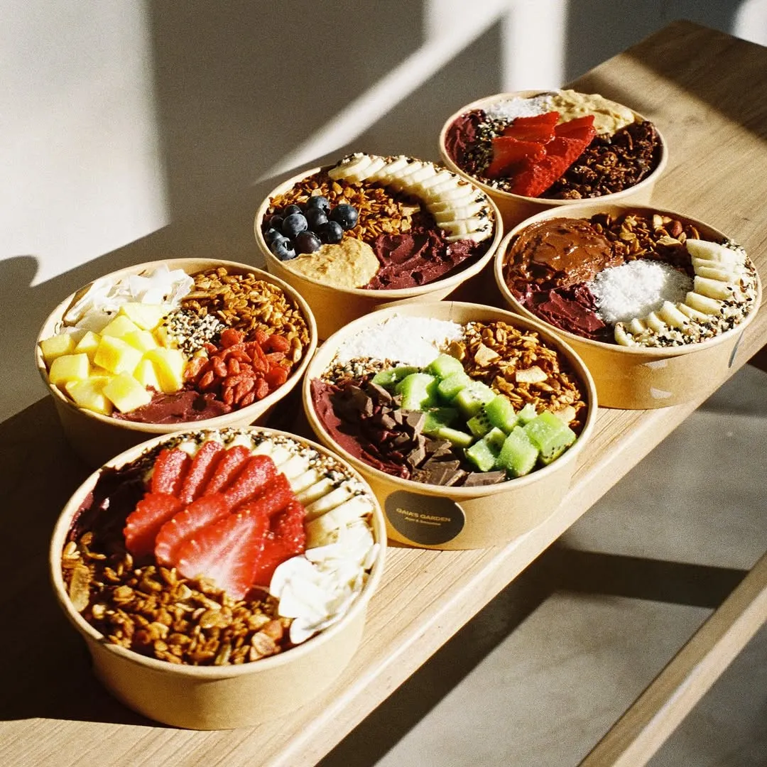 Seis açaí bowls de Gaia's Garden en fila, con fresa, kiwi, piña y granola